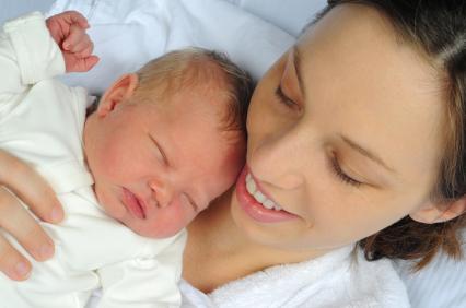 Woman on bed holding newborn baby