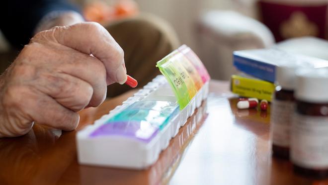 person filling daily pill dispenser