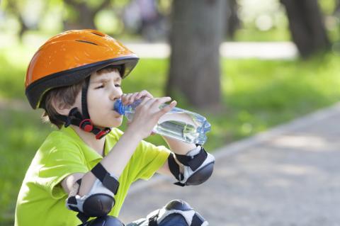 child wearing pads and helmet drinking water